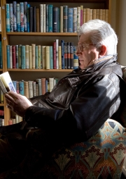 Older man reading in a armchair in a bookshop in Hay on Wye Engl