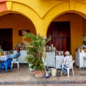 Locals sit by the store set out under the arches of a yellow building Cartagena, Colombia