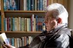 Older man reading in a armchair in a bookshop in Hay on Wye Engl