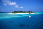 Alone yacht anchored in white blue waters by tiny island in Maldives Indian Ocean